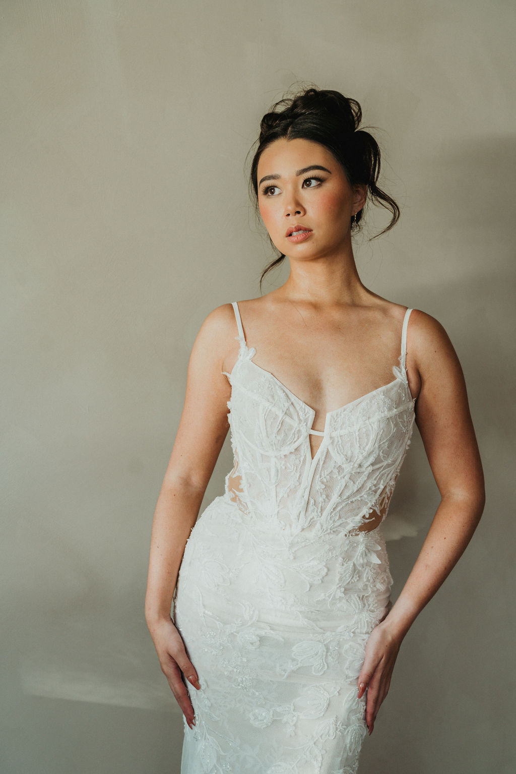 Editorial bridal portrait of a woman in a delicate lace gown with a softly pinned updo.